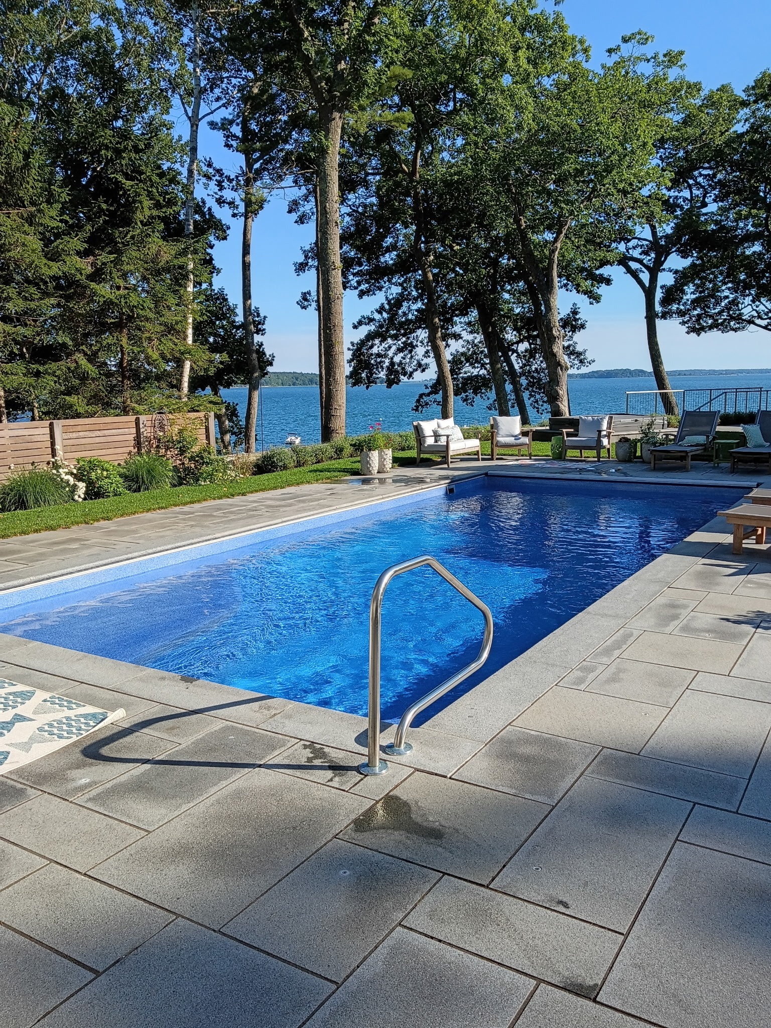 Poolside view with tall trees and a lake beyond