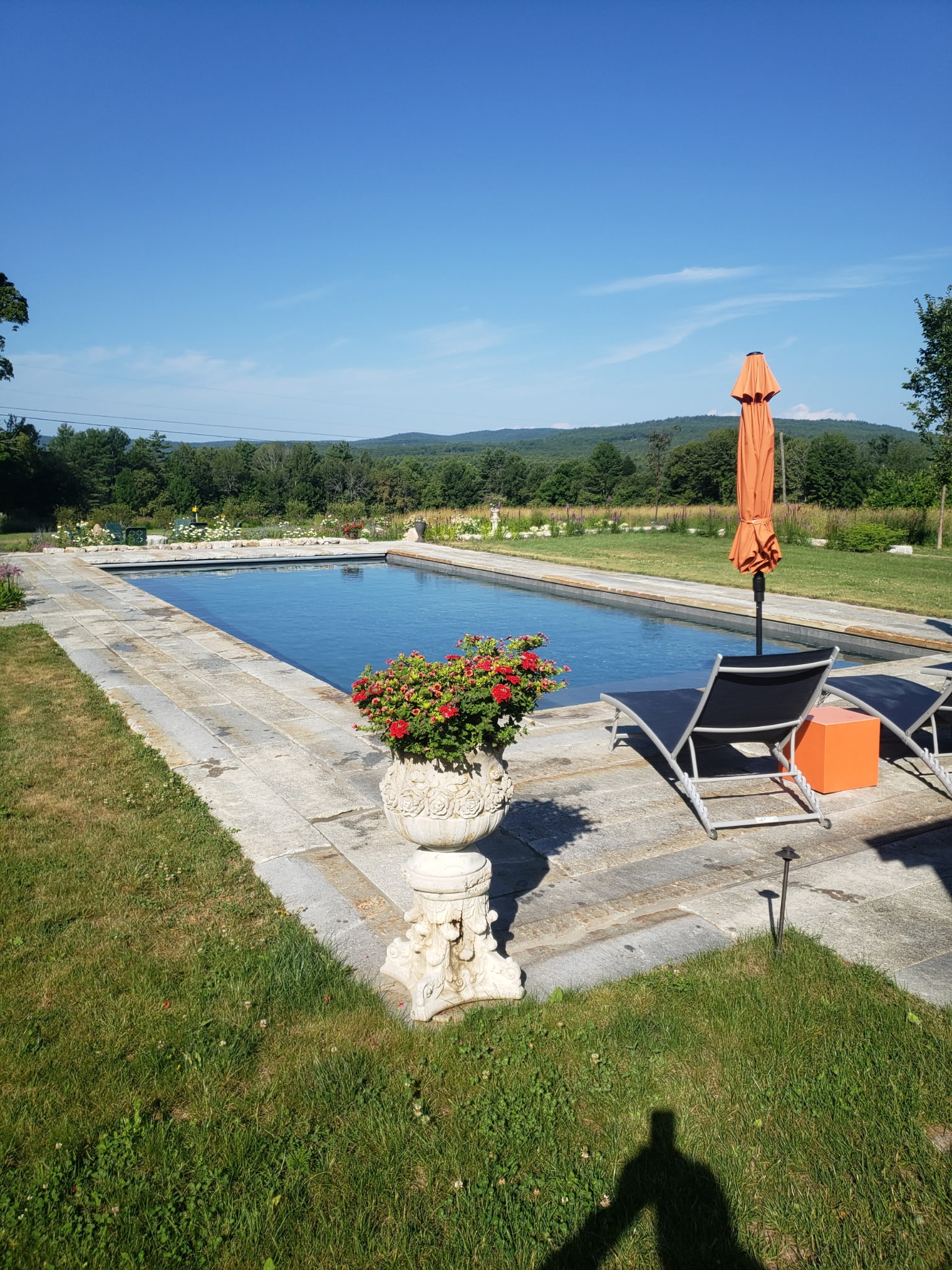 Outdoor pool framed by a broad Maine lawn and open sky