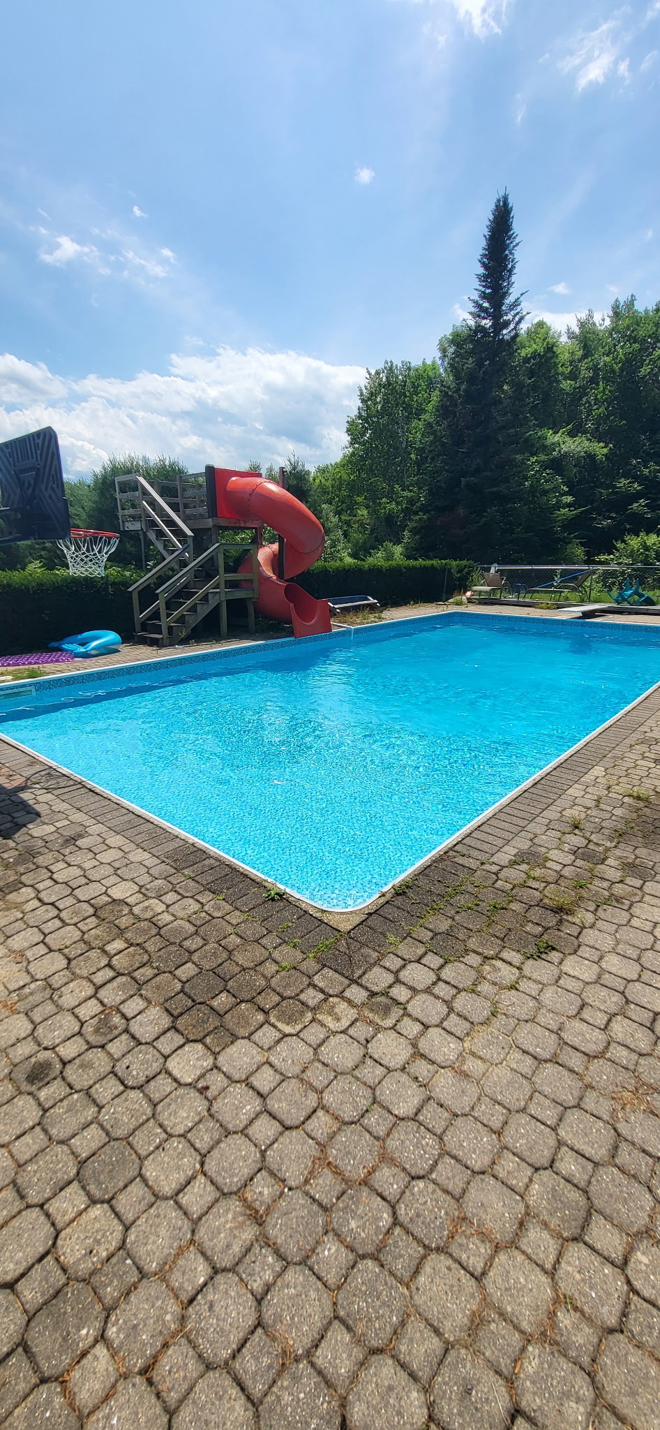 Blue backyard pool with a slide and stone patio